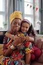 A loving embrace between a mother and daughter wearing vibrant traditional clothes indoors.