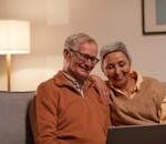 Senior couple enjoying time together on laptop indoors, smiling and relaxed.